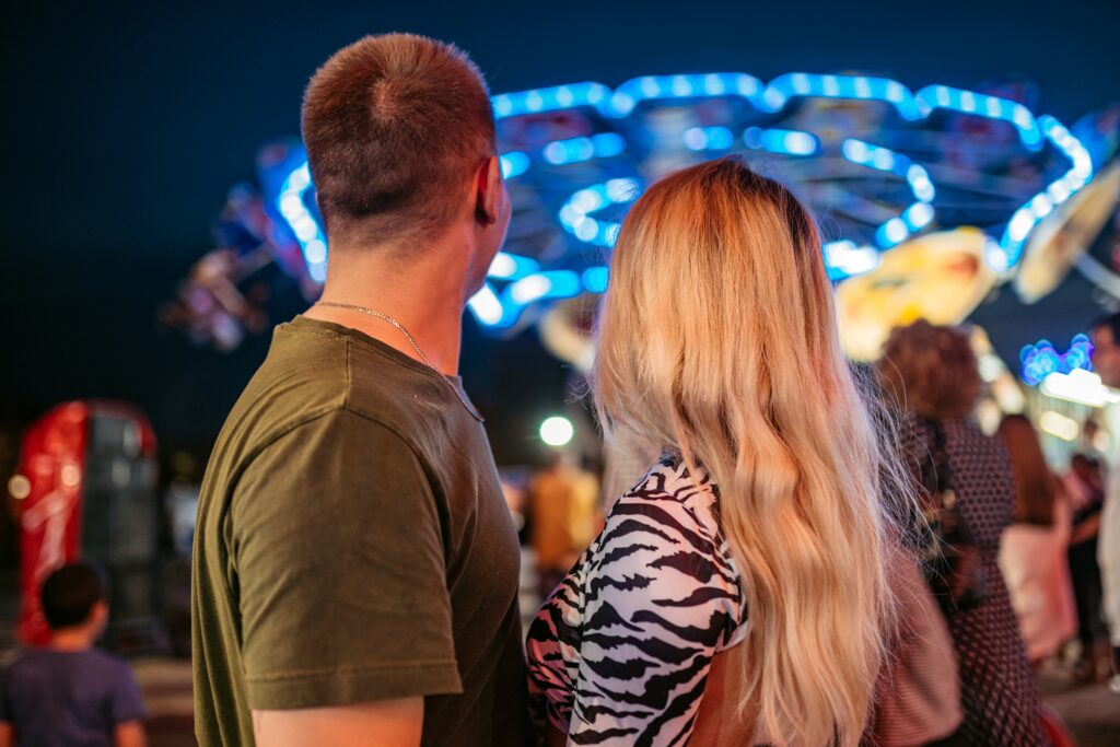 A young couple is pictured embracing as the crowd beyond them enjoys amusement park fun.
