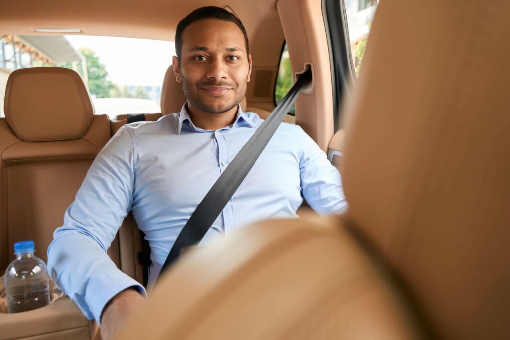 A man is pictured here buckled up in the back seat of a ride-share service vehicle.
