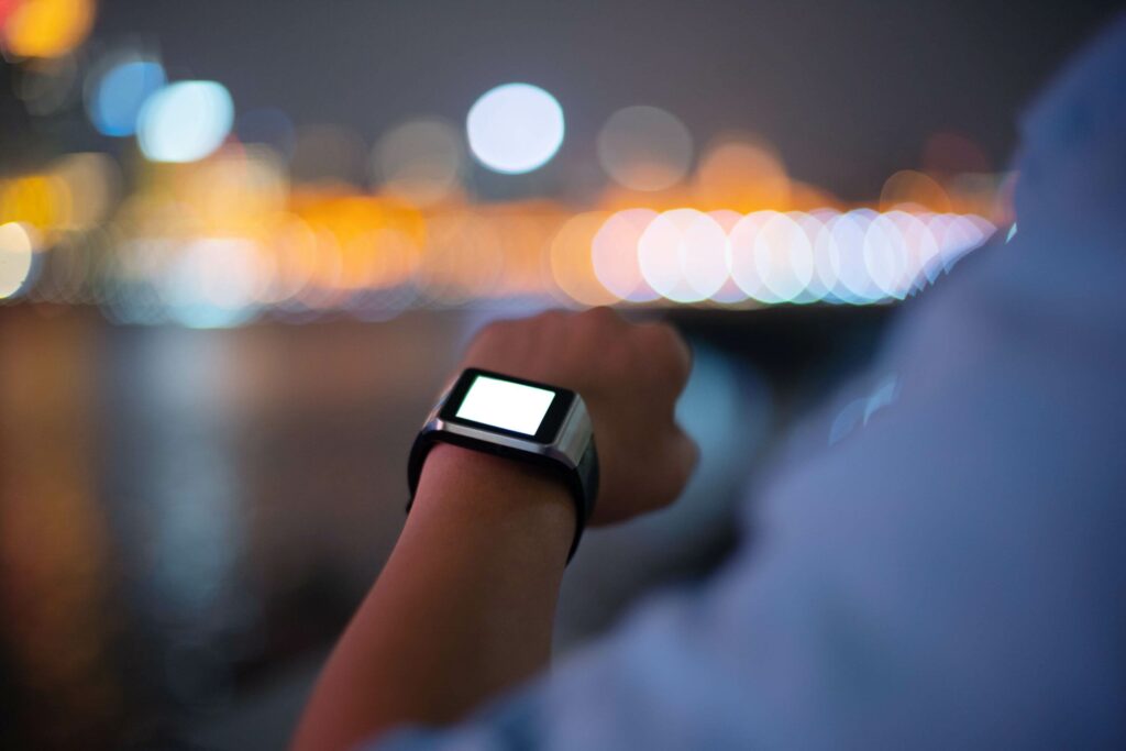 This is a photograph of a man pausing to look at his smartwatch during an evening walk.
