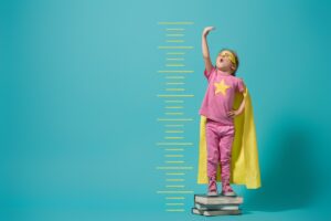 A little girl stands on top of some heavy books and stretches for the skies. She is dressed in a superhero costume. Provide education and training around fatigue, and you can be the safety superhero at your location.