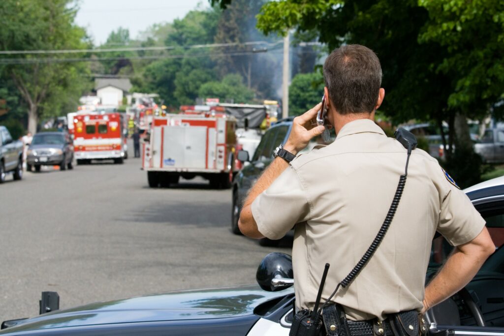 An officer secures the area while EMS personnel respond to a fire down the road.