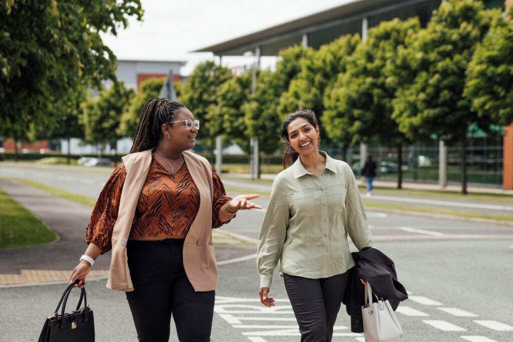 Two women are pictured here carrying on a conversation as they walk home from work.