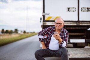 An older truck driver is pictured here surfing on the internet with his smartphone.