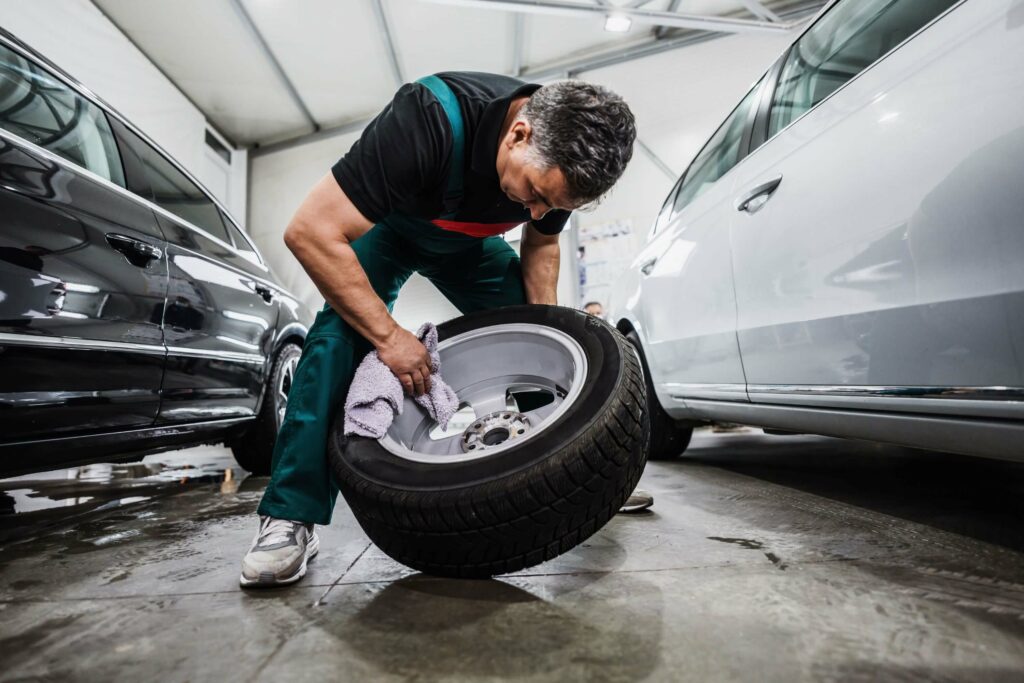 As part of a spring cleaning project, a man works to polish the rims of his tire wheels while in the garage.