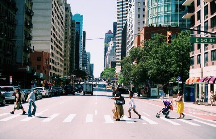 This is a photo of people using a crosswalk to cross the street during a typical work day.