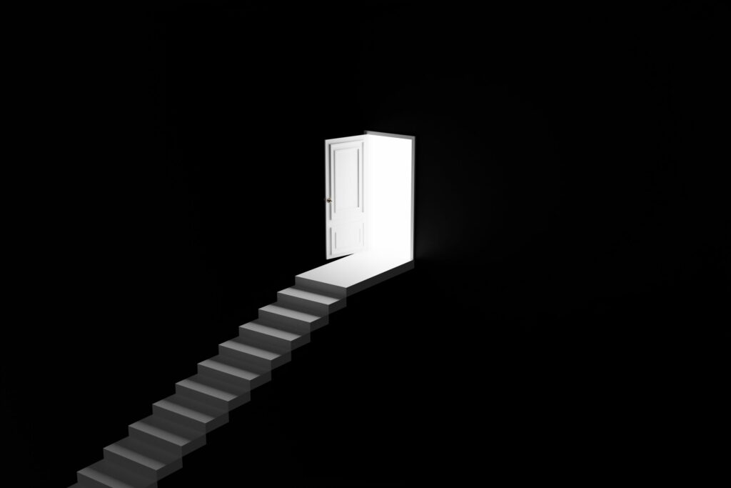 A stairway is pictured here rising to a open door, a flood of bright light shining to illustrate a bright future.