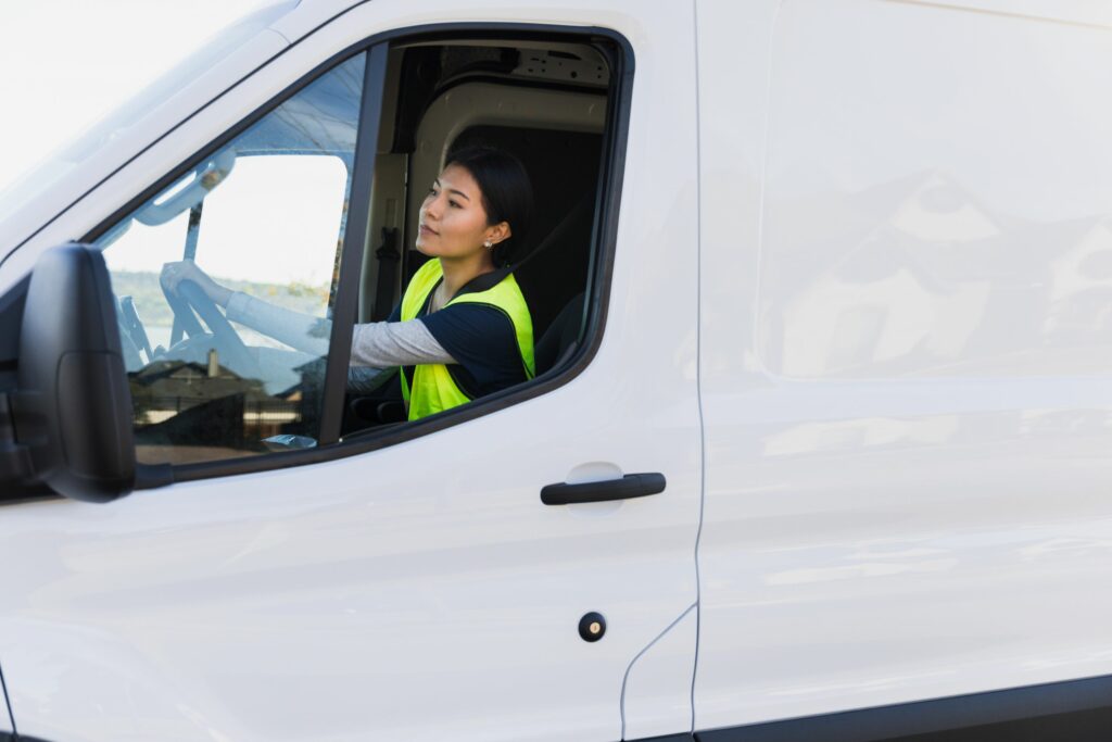 A young woman is pictured here driving a delivery van.