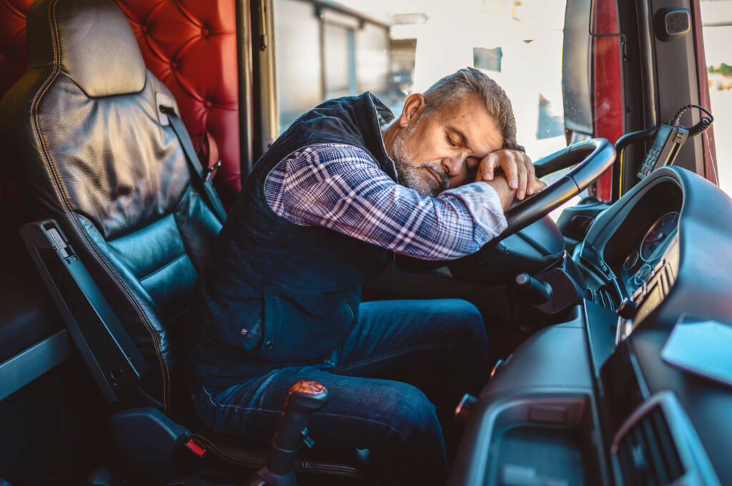 This is a photograph of a truck driver slumped over the steering wheel after spending an exhausting day on the job.