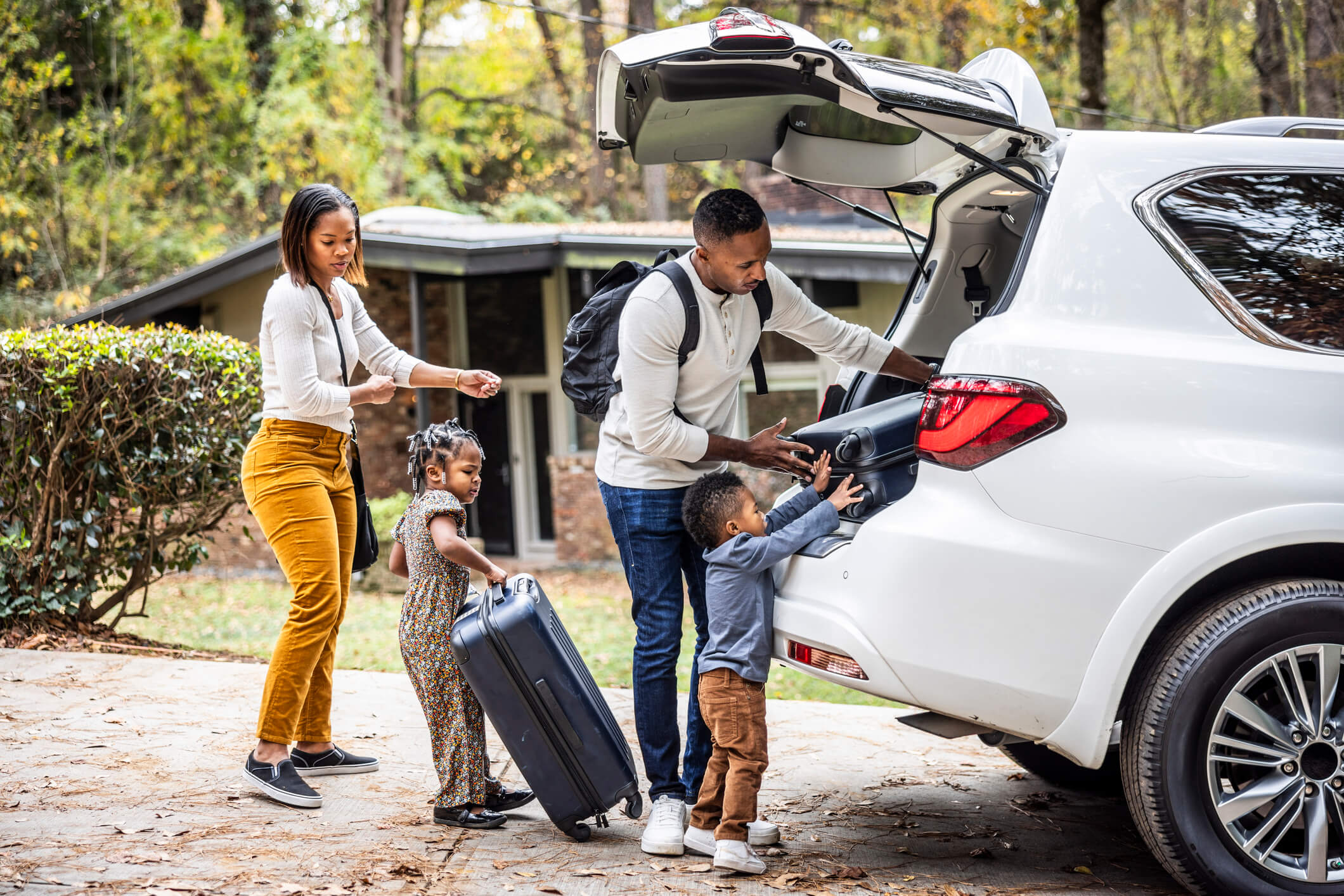 A family is pictured here packing bags into a SUV ahead of a road trip.