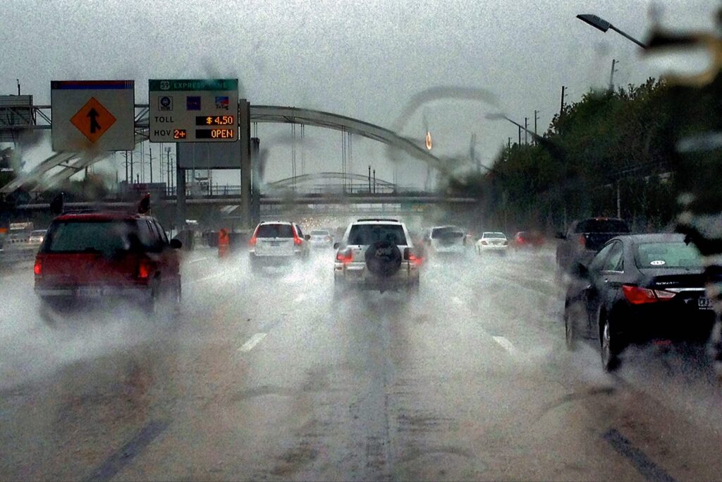 Vehicles in this scene are pictured splashing up water as rain falls on a Houston freeway.