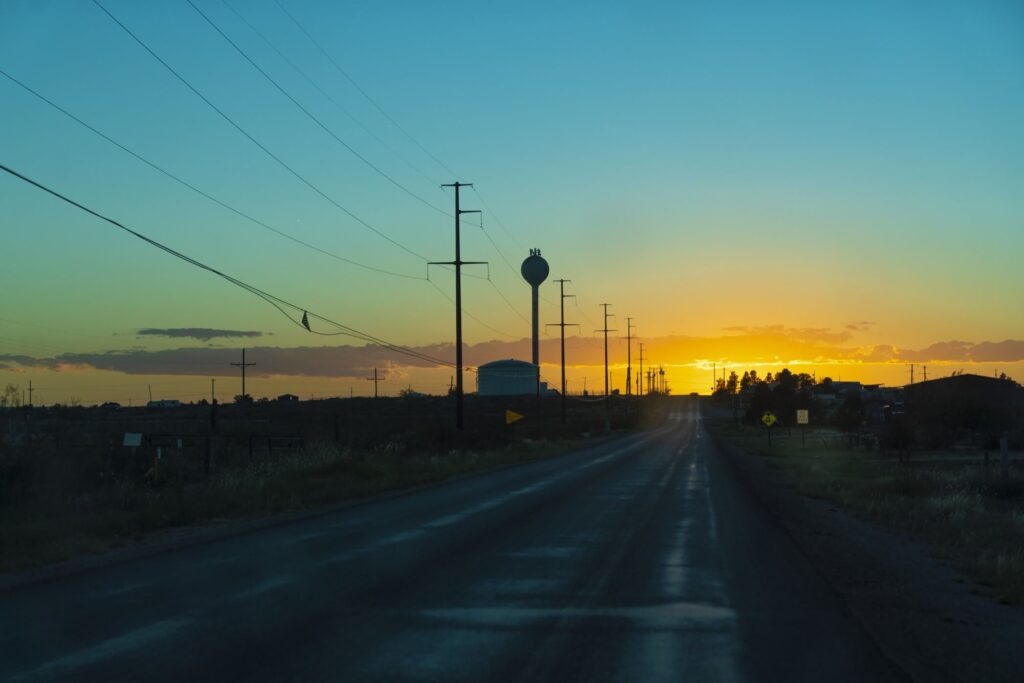 A rural road is pictured with the sun setting here in the distance.