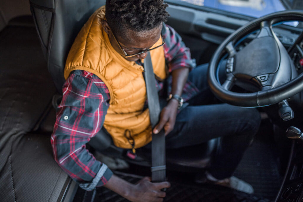 A worker fastens his seat belt before starting on his delivery route.